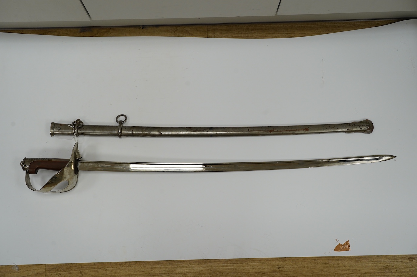 An Italian WWI cavalry trooper’s sword, pipe back blade, pierced guard, wooden grip, in its steel scabbard, blade 91cm. Condition - fair